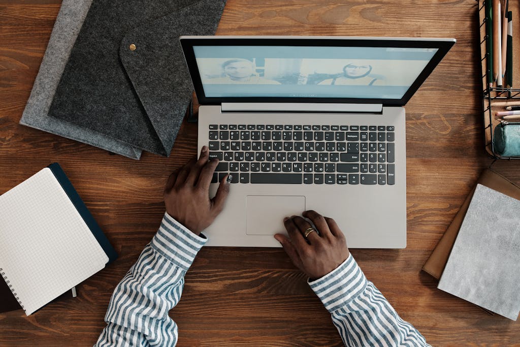 Top view of person on a video call using a laptop with hands on keyboard. Ideal for work-from-home themes.