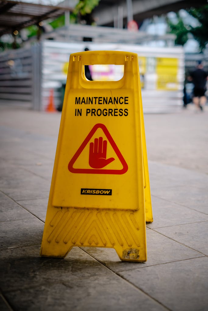 Yellow maintenance sign with red hand symbol on Jakarta street.